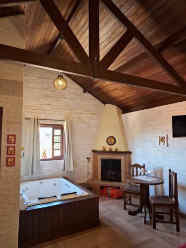 a large room with a tub and a fireplace at Pousada Encanto da Serra in Monte Verde