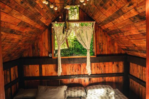 a bedroom in a wooden cabin with a window at Fazenda Alegria Camping & Aventura in Rio de Janeiro