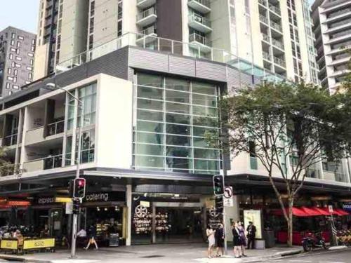 a building on a city street with people standing outside at Prime location - CBD Brisbane 1 bed w shared 25m pool, gym, sundeck and a BBQ area in Brisbane