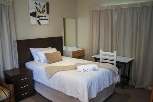 een slaapkamer met een bed en een bureau met handdoeken bij Villa La Sola B&B and Self-Catering in Boksburg