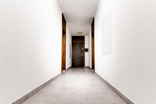an empty corridor with white walls and a black door at Hop & Lulu Premium Apartments in Gollnow