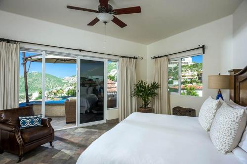 a bedroom with a white bed and a large window at Sunset View Villa Pedregal in Cabo San Lucas