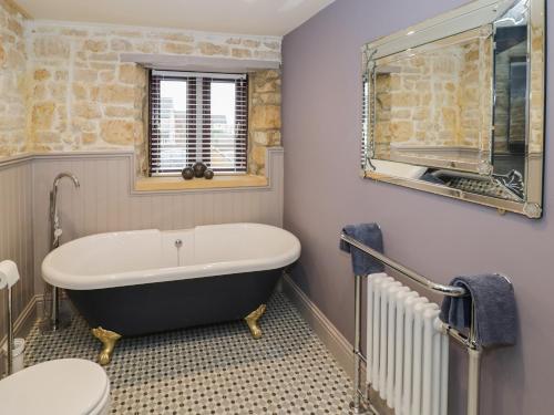 a bathroom with a bath tub and a toilet at Bow Cottage in Cheltenham
