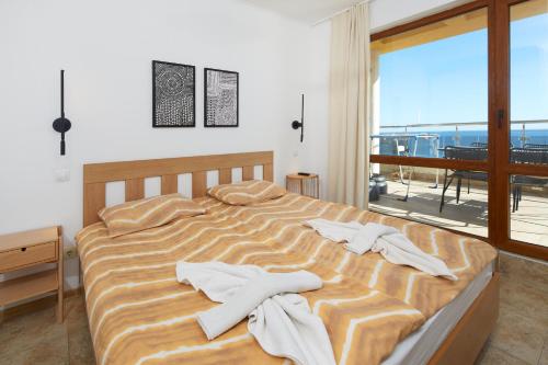 a bedroom with a bed with towels on it at Infinity Apartment Nessebar in Nesebar