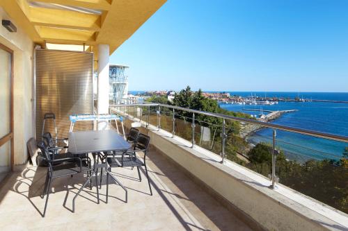 a balcony with a table and chairs and the ocean at Infinity Terrace 1BR Apartment Nessebar in Nesebar