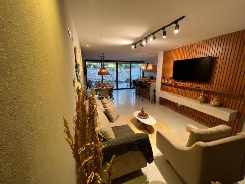 a living room with a couch and a tv at Kanui Casa Maré 107 in São Miguel dos Milagres