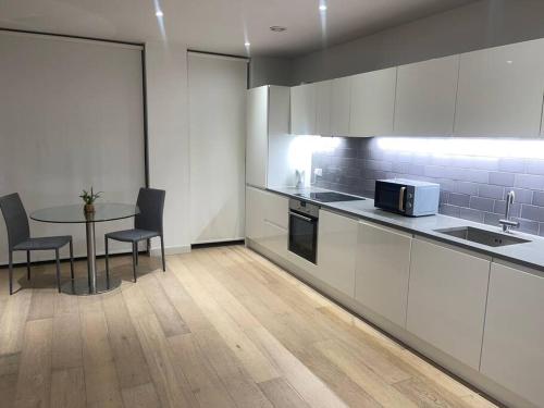 a kitchen with white cabinets and a table with chairs at Stunning 2 Bedroom Apartment in London