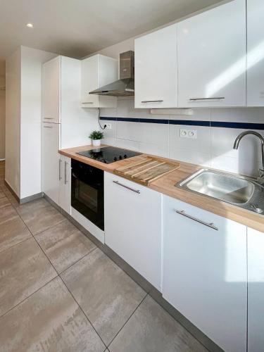 une cuisine avec des armoires blanches et un évier dans l'établissement Appart'hodromme Longchamp, à Rennes