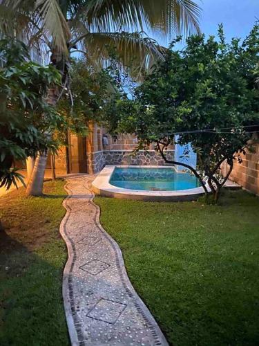 a garden with a stone path leading to a swimming pool at Casa Emilia in Yautepec