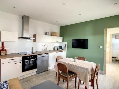 a kitchen with a table and chairs and a kitchen with green walls at Appartement aux salins du lion in Vitrolles