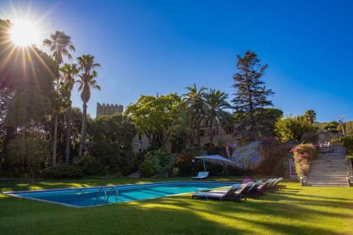 einen Pool in einem Garten mit Palmen in der Unterkunft Castillo de Meng the Castle Experience in Cabrils