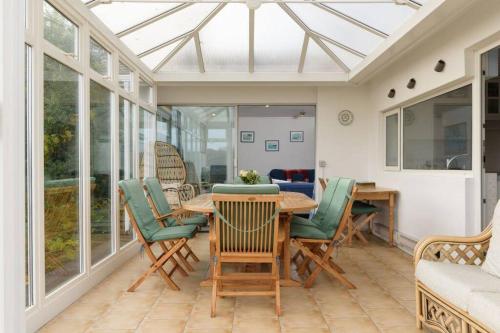 a conservatory with a table and chairs on a patio at Stunning River Views, Tranquil Split-Level House, Private Garden & Parking in Golant