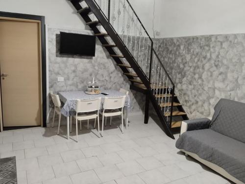 uma sala de jantar com uma mesa com cadeiras e uma escada em House Lurokè em Catânia