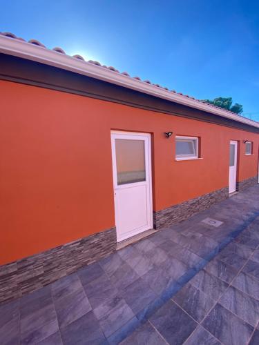 a orange building with a white door on it at Casa dos Diogos II in Grândola