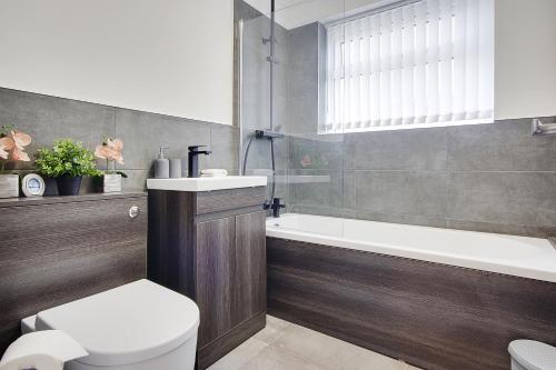 a bathroom with a toilet and a tub and a sink at 17 Banstead Road in Poole