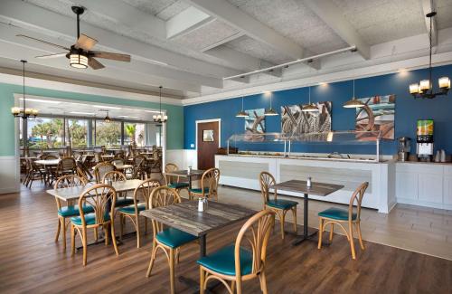 ein Restaurant mit Tischen und Stühlen und blauen Wänden in der Unterkunft Dayton House Resort - BW Signature Collection in Myrtle Beach