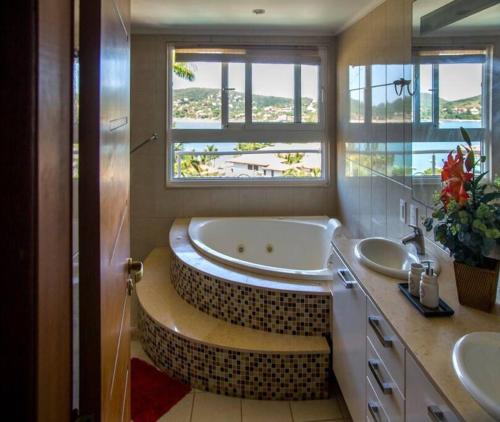 baño con bañera, 2 lavabos y ventana en Maravilhosa Mansão em Frente à Praia da Ferradura Por Luxury Rentals en Búzios