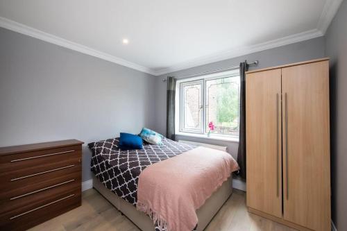 a bedroom with a bed and a dresser and a window at Cozy 2-Bedroom Flat in Battersea in London