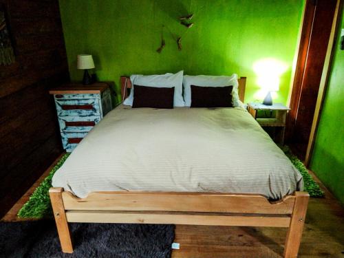 a bedroom with a large bed with a green wall at Hostal & Cabañas Luna del Sur in Cucao