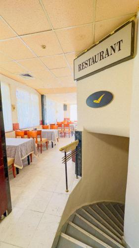 a restaurant with a staircase in a room with tables and chairs at Dezudava Family Hotel in Sandanski
