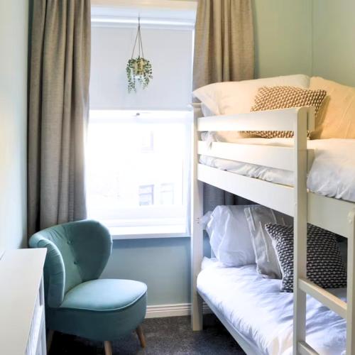 ein Schlafzimmer mit einem Etagenbett und einem Stuhl in der Unterkunft Avocet Cottage Amble in Amble