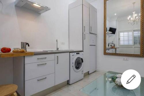 a white kitchen with a washing machine and a mirror at Fernando IV 29A in Seville
