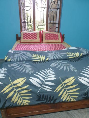 a bed with a blue bedspread with leaves on it at Villa westcost tembewadda colomb in Canacona