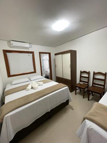 a bedroom with a large bed and two chairs at Escalada Hospedagem Térreo in Mucugê
