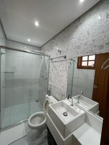 a bathroom with a sink and a toilet and a shower at Escalada Hospedagem Térreo in Mucugê