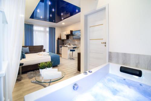 a bathroom with a tub and a bedroom at Elegante Apartments Władysławowo in Władysławowo