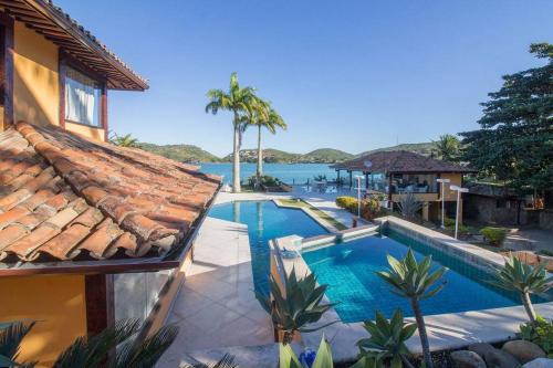 uma casa com piscina junto à água em Cinematográfica Mansão Pé na Areia da Ferradura com Treze Quartos Por Luxury Rentals em Búzios