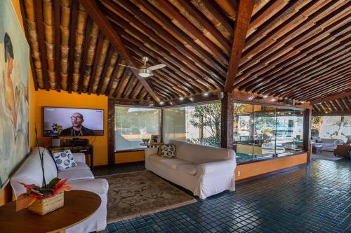 uma sala de estar com 2 sofás e uma televisão de ecrã plano em Cinematográfica Mansão Pé na Areia da Ferradura com Treze Quartos Por Luxury Rentals em Búzios