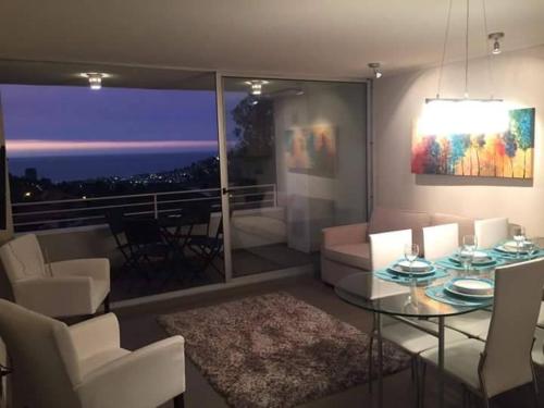 sala de estar con mesa, sillas y vistas en Departamento Costa Reñaca, en Viña del Mar