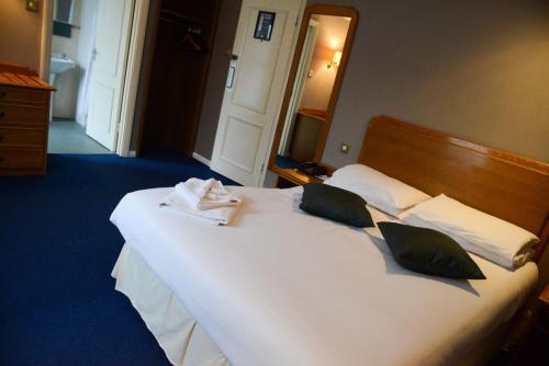 a bedroom with a large white bed with towels on it at Preston Park Hotel in Brighton & Hove