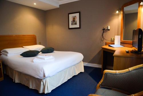 ブライトン＆ホーブにあるPreston Park Hotelのベッドとデスクが備わるホテルルームです。