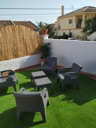 un patio con sillas y mesas en el césped en PIT STOP en Málaga