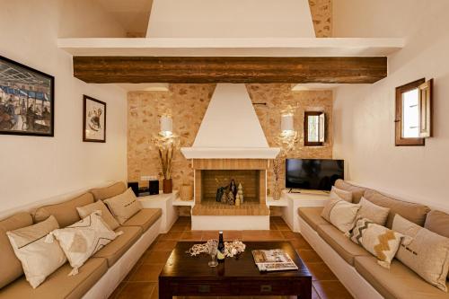 een woonkamer met een bank en een open haard bij Can Noves - Villa de 5 suites 28 y 58 in Sant Francesc Xavier