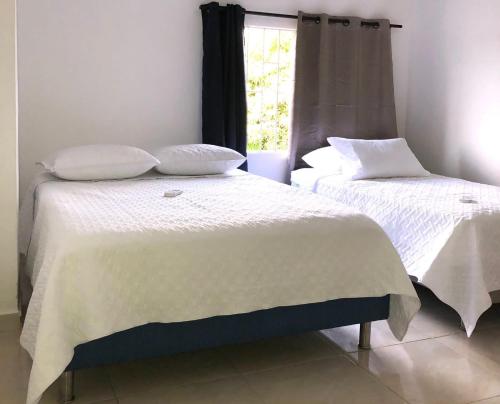1 dormitorio con 2 camas con sábanas blancas y ventana en Hotel Samark Valledupar, en Valledupar
