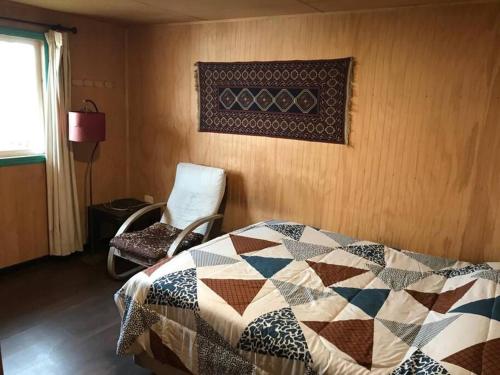 1 dormitorio con edredón en la cama y silla en Cabaña 2D-2B Vista única, en Teguaco