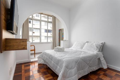 a white bedroom with a bed and a window at Apartamento aconchegante em Copacabana - Rio de Janeiro in Rio de Janeiro