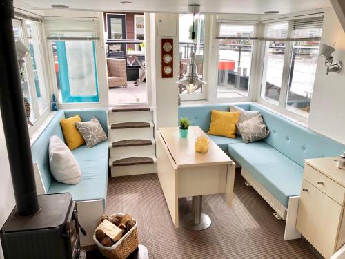 a living room with a blue couch and windows at Het VaarHuis - Beachclub Sneek in Offingawier