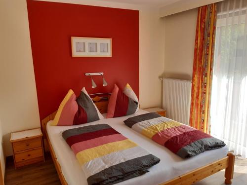 ein Schlafzimmer mit einem Bett mit einer roten Wand in der Unterkunft Haus Sommerstein in Maria Alm am Steinernen Meer