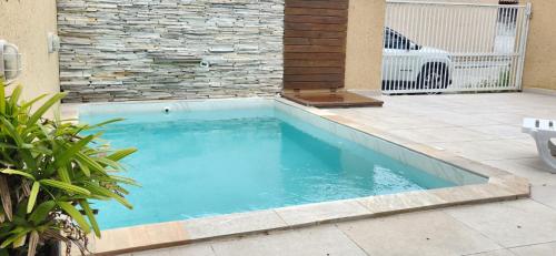 a swimming pool in a yard with a stone wall at Linda casa no baln. Ponta do papagaio a 100m do mar in Palhoça