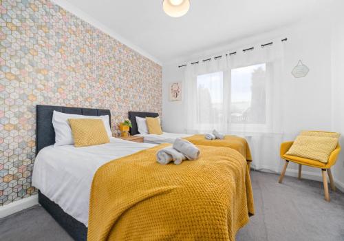 a bedroom with two beds with yellow blankets at Anderson Apartment by Klass Living Motherwell in Motherwell