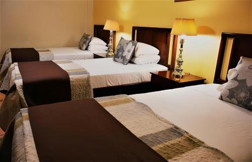 a hotel room with three beds and a table at Hotel Puerta del Sol - San Jose Airport in San José