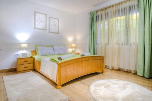a bedroom with a bed and a window with green curtains at Pavle's Oasis in Virpazar