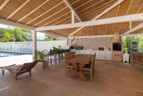 a kitchen and dining room with a wooden table and chairs at Mansão Pé na Areia da Ferradura Por Luxury Rentals in Búzios