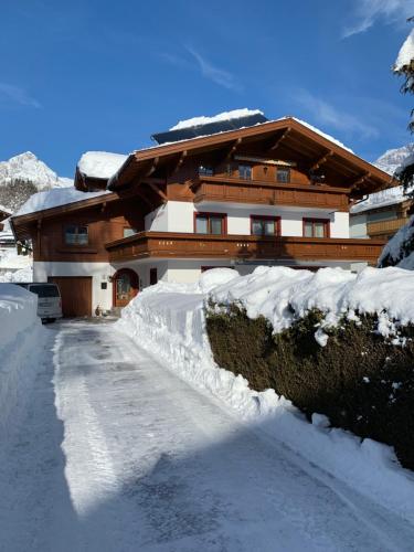 una casa está cubierta de nieve con una entrada en Haus Sommerstein, en Maria Alm am Steinernen Meer