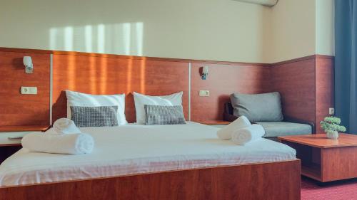 a bedroom with a large bed with two pillows on it at Dezudava Family Hotel in Sandanski