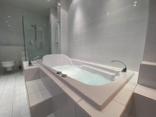 a white bathroom with a tub and a toilet at Exklusives Penthouse 232QM Whirlpool 28min bis Düsseldorf Messe in Mönchengladbach